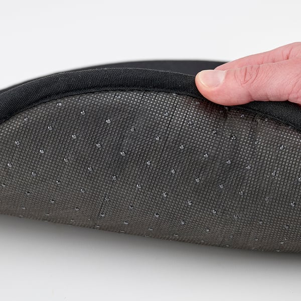 Hand pressing black mesh chair pad, showing anti-slip back texture.