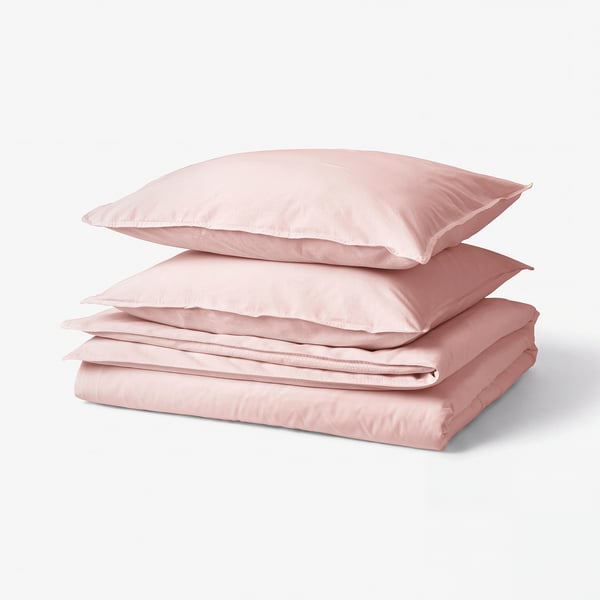 A neatly stacked pink bed linen set, including a duvet cover and pillowcases, made of soft, recycled cotton.
