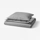 A neatly folded grey duvet set with pillowcase, featuring soft, washed cotton by ÄNGSLILJA.