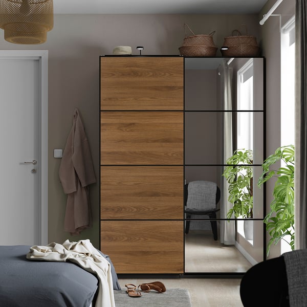 Modern bedroom with AULI sliding wardrobe, mirrored & wooden panels by bed.