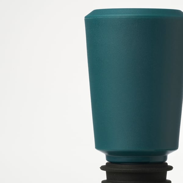 Close-up of a green silicone stopper for sealing bottles. Smooth surface visible, designed to preserve beverages.