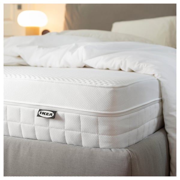 IKEAs white rolled mattress, labelled ÅVABERG, showcased on a bed.