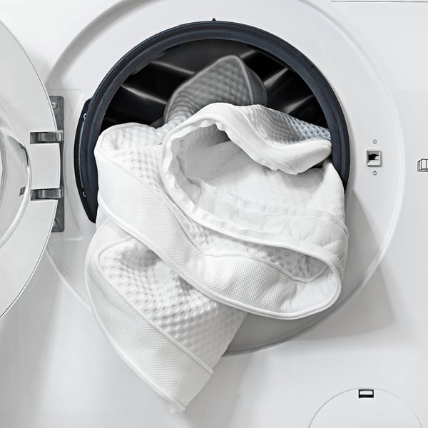Washing machine with open door showing folded white blanket inside.