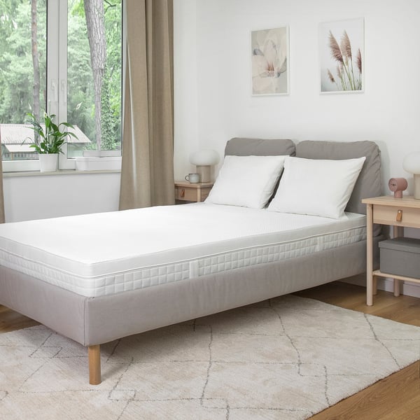 Minimalist bedroom with white bed, nightstands, lamps, and forest view.