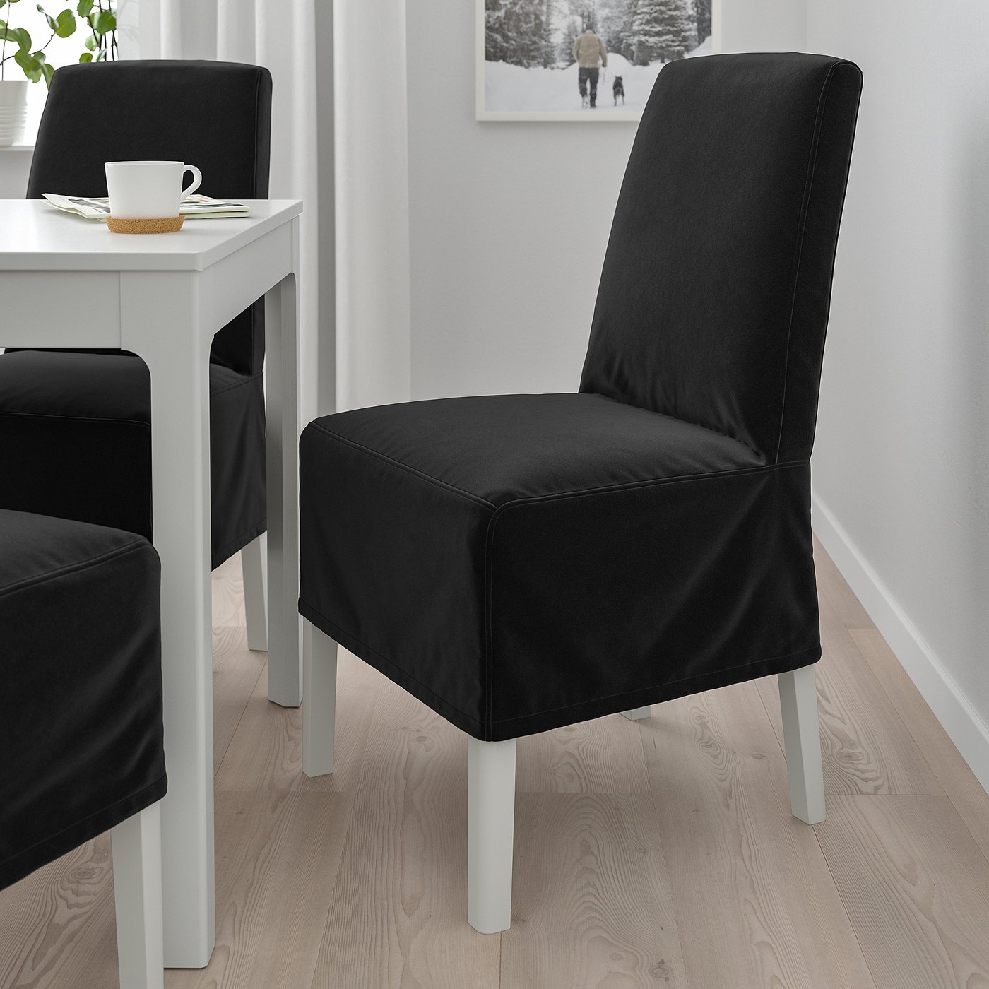 Two large black BERGMUND chairs with metal legs near small white table with coffee cup.