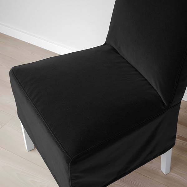 Modern black chair with sleek design, soft upholstery, and sturdy legs on wooden floor.