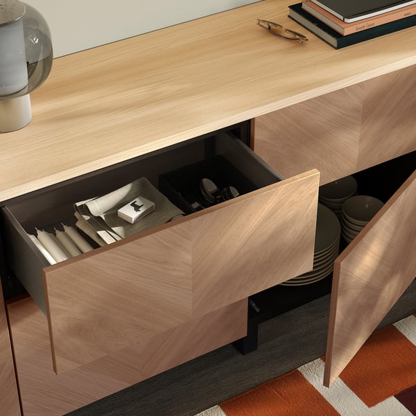 Wooden drawer partially open showing organised items: candles, boxes, and coasters. Top has decorative items.