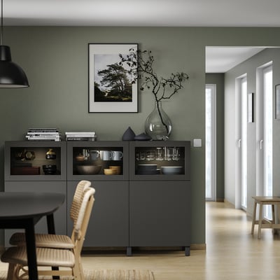 Modern living room with grey BESTÅ units, wood floors, green walls, black pendant lamp, and glass showcase.