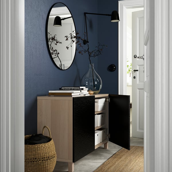 Modern entryway with BESTÅ sideboard, open storage, mirror, and vase of flowers.