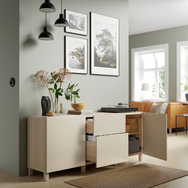 Modern living room with BESTÅ sideboard displaying turntable, vase, bowl, framed photos, and black lamps.