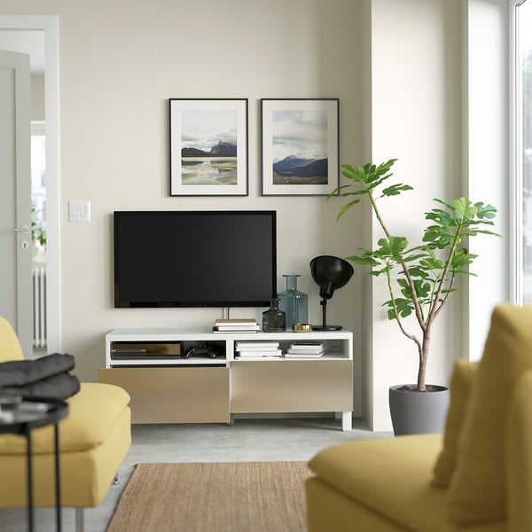 Modern living room with yellow chairs, flat-screen tv on white BESTÅ stand, featuring drawers for storage and cable management.