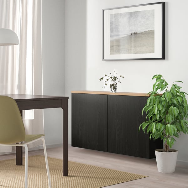 Modern living room with black ikea BESTÅ unit, plant, light wood floor, natural light.