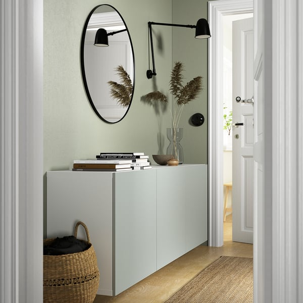 Wall-mounted BESTÅ cabinet with books, vase, mirror, and basket - hallway storage.
