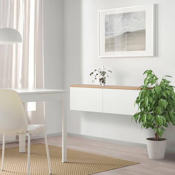 Minimalist white desk with chair, plant, and artwork, ideal for modern spaces.