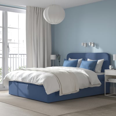 Blue bed with white linens, large window, hanging light.