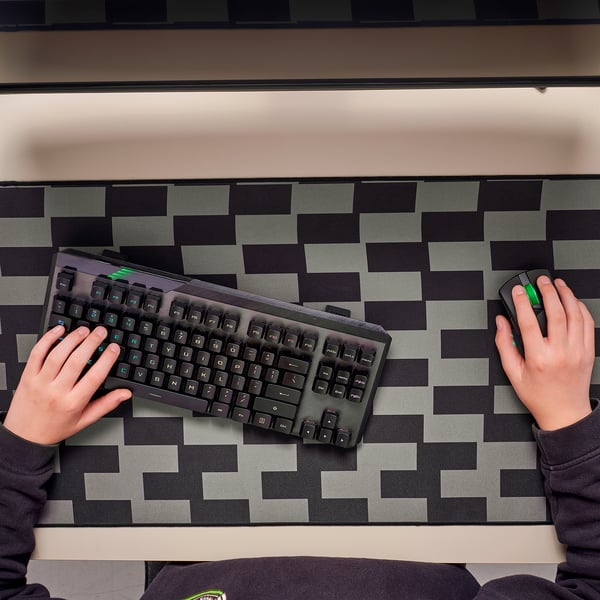 Person typing and using mouse on chequered gaming pad.