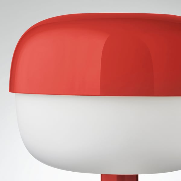 A modern red table lamp with a smooth, sleek design, emitting a soft, inviting light.