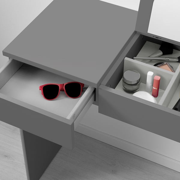 Open desk with red sunglasses left drawer, make-up right drawer, grey top.