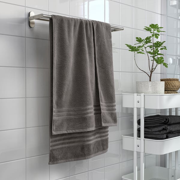 A BROKGLIM grey towel on a metal rod, large, soft, absorbent, organic cotton with woven border in bathroom.