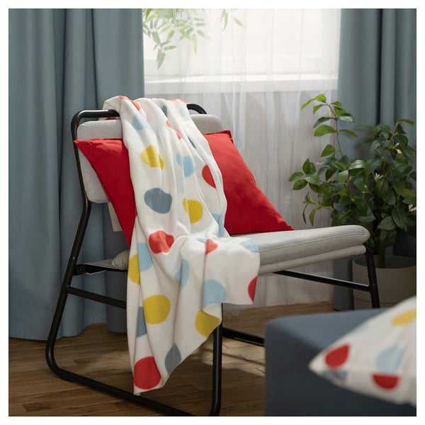 Cosy living room with recycled polyester chair and colourful polka-dot blanket.