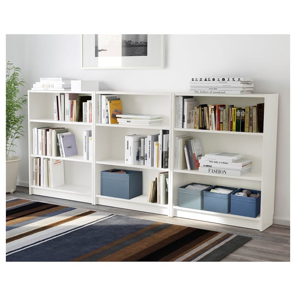 White bookshelf with books and blue storage boxes.