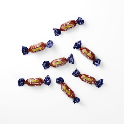 Several individually wrapped chocolate treats named DUMLE scattered on a white surface.
