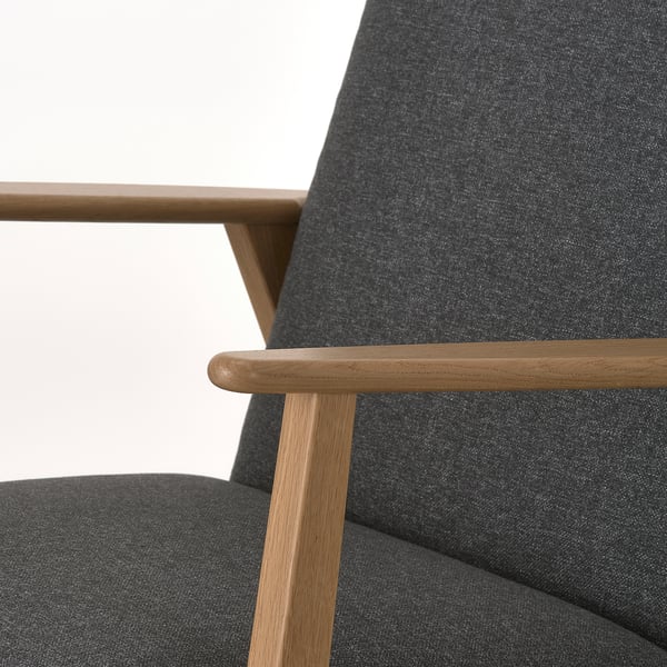 Close-up of stylish, solid oak armchair with modern retro design, soft grey upholstery, and sturdy craftsmanship.