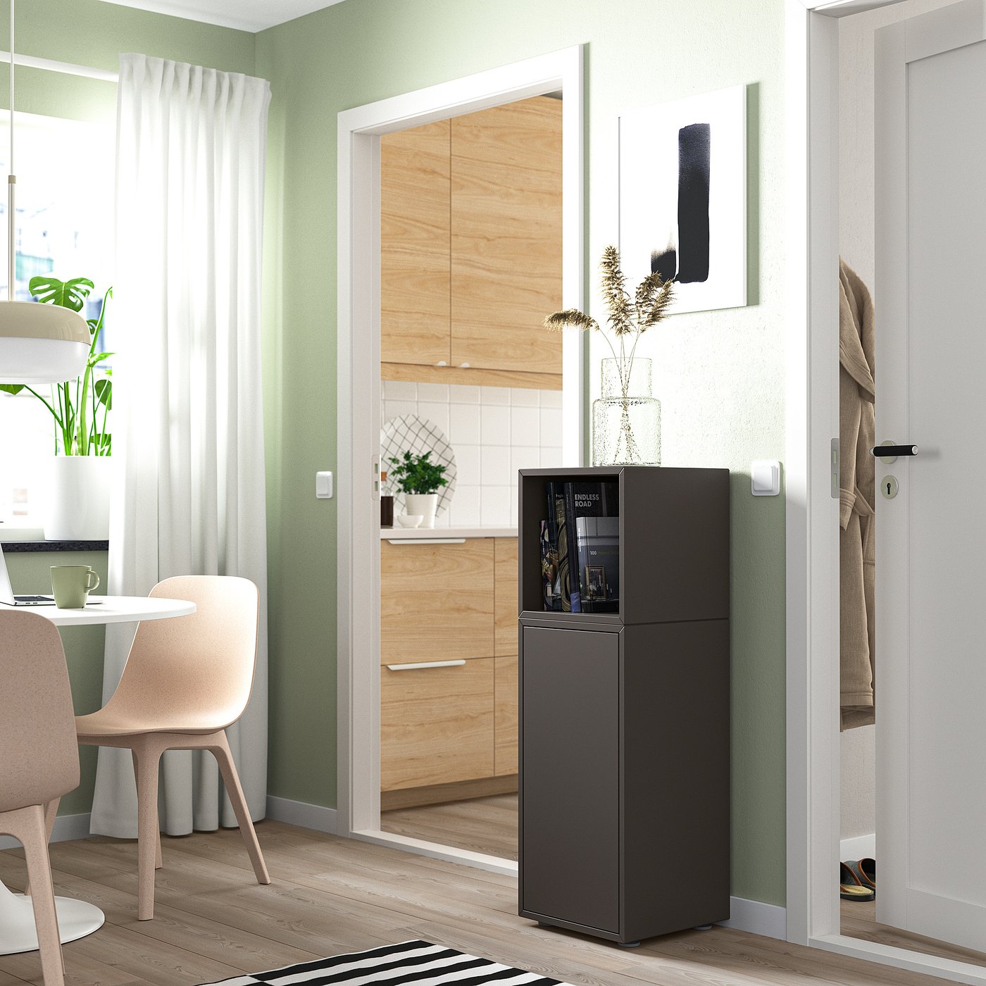 Black EKET storage unit in kitchen, smaller than adjacent cabinets, with dried flowers on top.