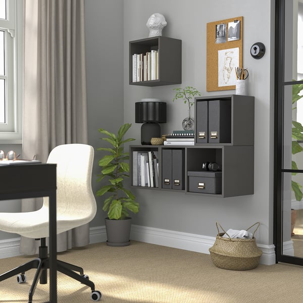 Home office with dark grey EKET shelves. Plants, basket, and white desk/chair setup nearby a large window.