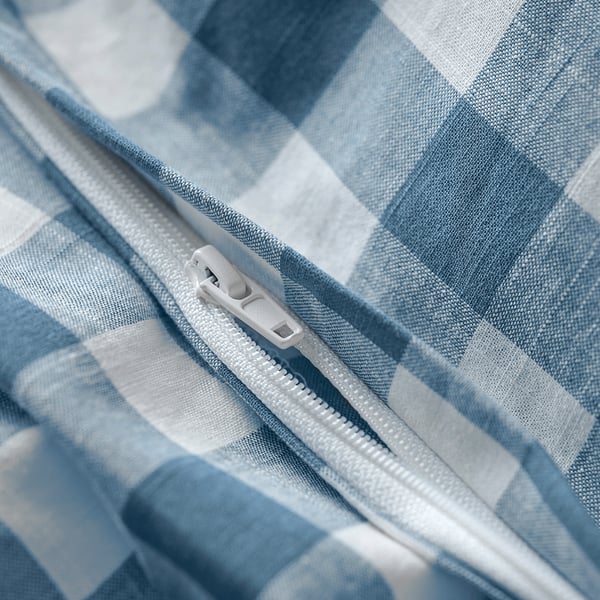Close-up of a zip on a blue and white chequered duvet, showing its functional closure detail.