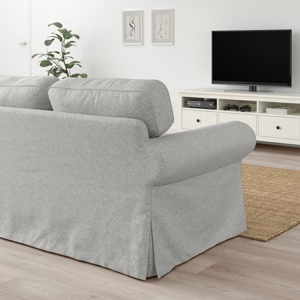 Grey EKTORP sofa with cushions, tv console, rug, and plant.