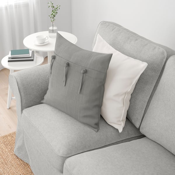 Grey sofa with EKTORP cushions, white coffee table with books.