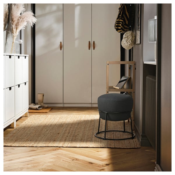 Black EMMISLÖV pouffe near shelves and cabinet.
