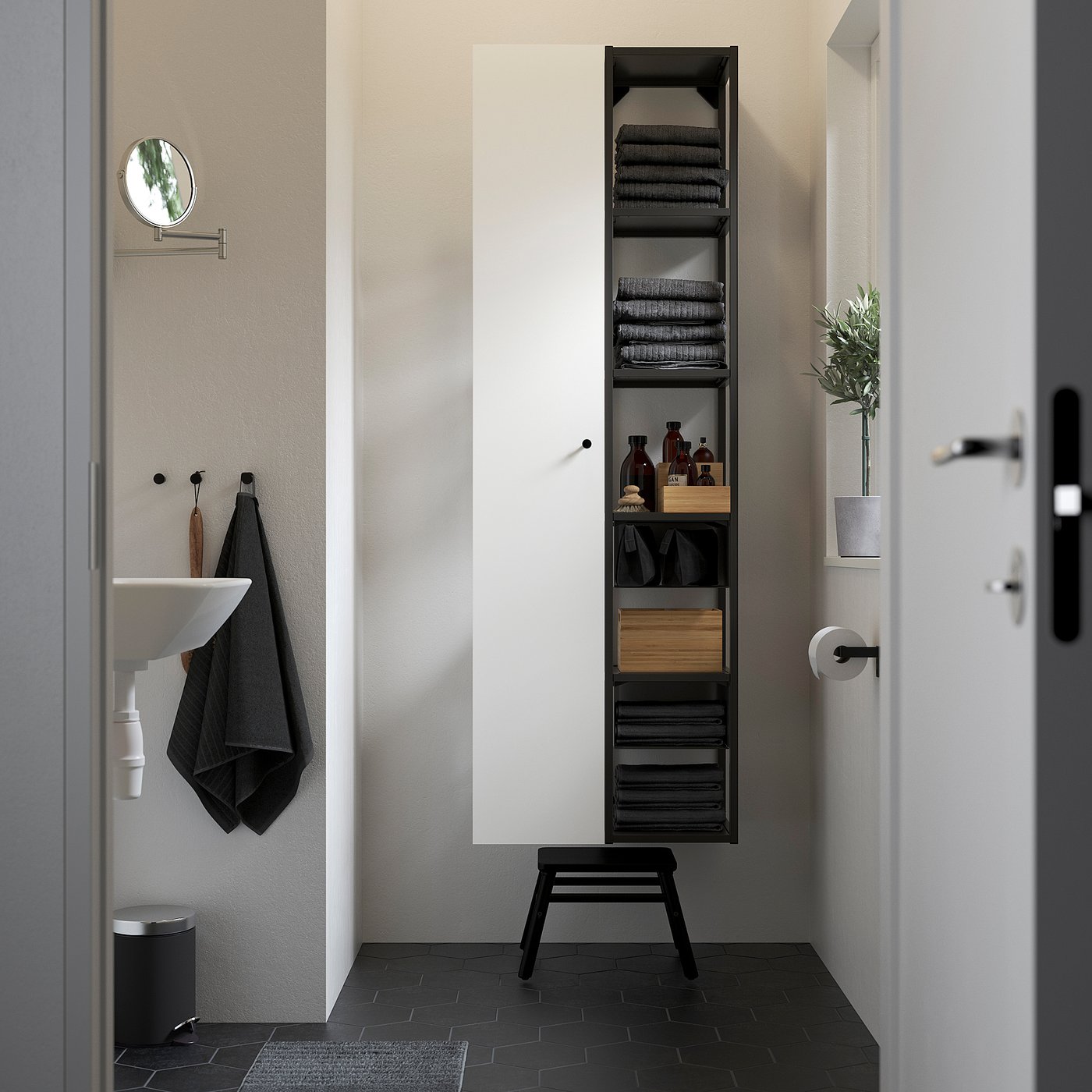 Modern bathroom with tall black metal storage, towels, sink, and dark floor tiles.