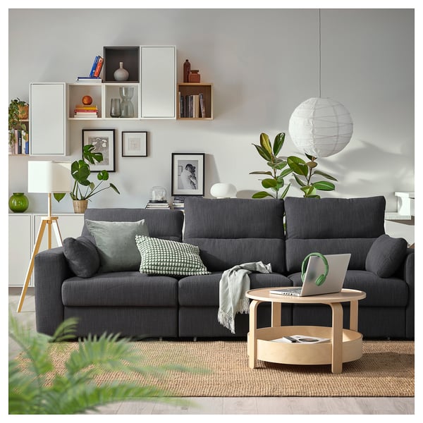 Modern living room with dark grey ESKILSTUNA sofa, wooden coffee table, stylish decor, and plants.