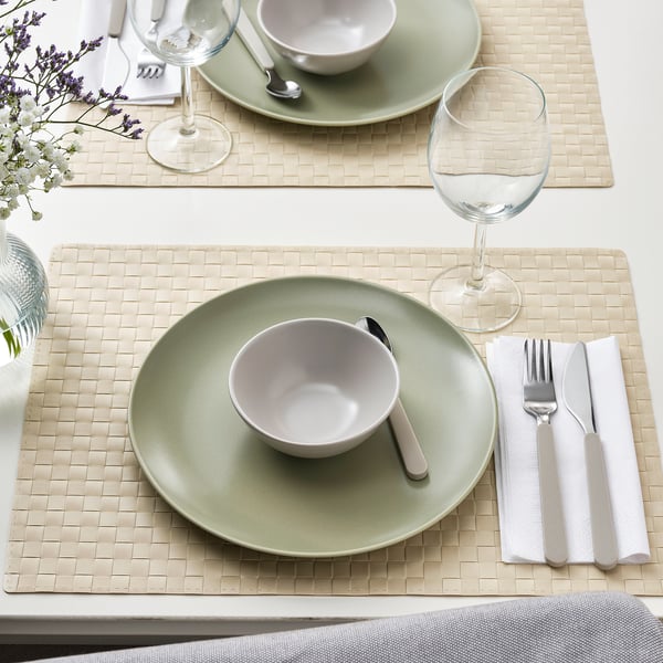 Table setting with green plates, bowls, cutlery, and wine glasses.