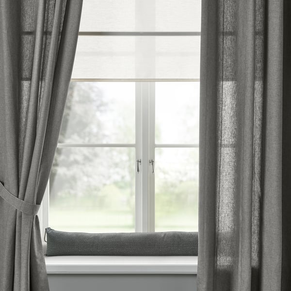 Modern window with grey curtains and cushion; minimalist design.