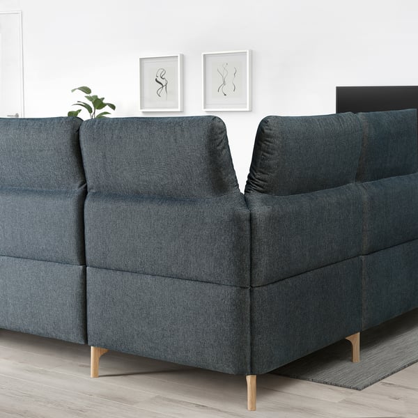 Dark blue FAMMARP sofa with adjustable headrests and wooden legs, minimalist wall art.