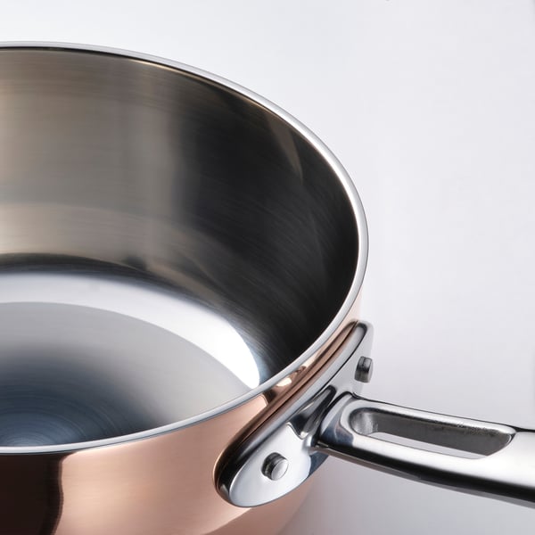 Copper saucepan with stainless handle, polished interior, sturdy and efficient.