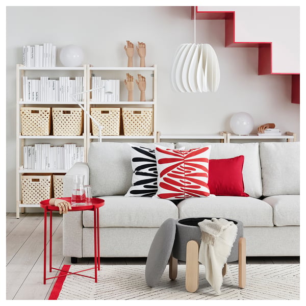 Modern living room with a light grey FÖRLUNDA sofa, red accents, white bookshelf, red side table, and a grey storage ottoman.