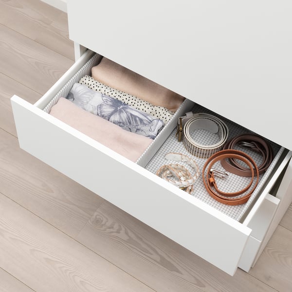 Open wardrobe drawer showing neatly folded clothes, accessories, and belts.