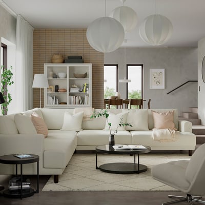 Modern living room with l-shaped white couch, black side table, and brick wall.