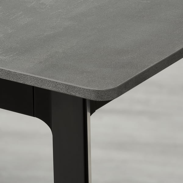 Close-up of extendable dining tables sleek, textured edge and sturdy black leg.