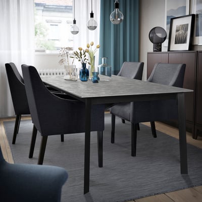 Modern dining area with extendable table, chairs, blue rug, bulbs, and curtains.