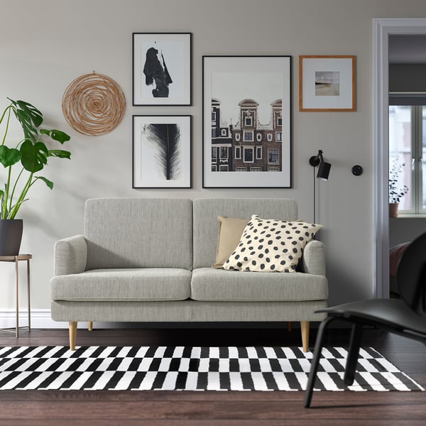 Modern living room with GRILLSTORP 2-seat grey sofa, art wall, rug, and plant.
