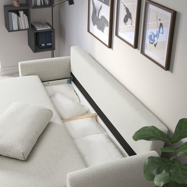 GRUNNARP sofa-bed with cushions out, showing seating and sleeping areas. Artwork and shelves in background.