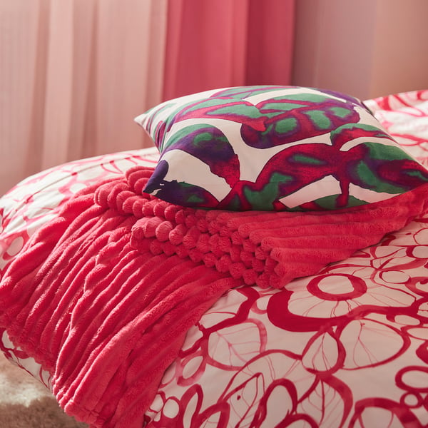 A pink, soft, and cosy bedspread with a textured, fluffy surface on a bed, giving a sense of warmth and comfort.