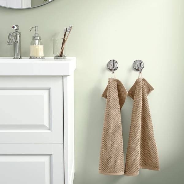 Bathroom with white cabinet, 2 soft beige GULVIAL cotton towels, soap dispenser & toothbrush holder.