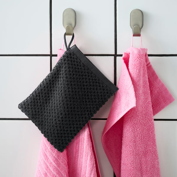 Hang two GULVIAL mitts: pink and grey, soft cotton, square, with loops, on grid wall hooks. Pink one larger.