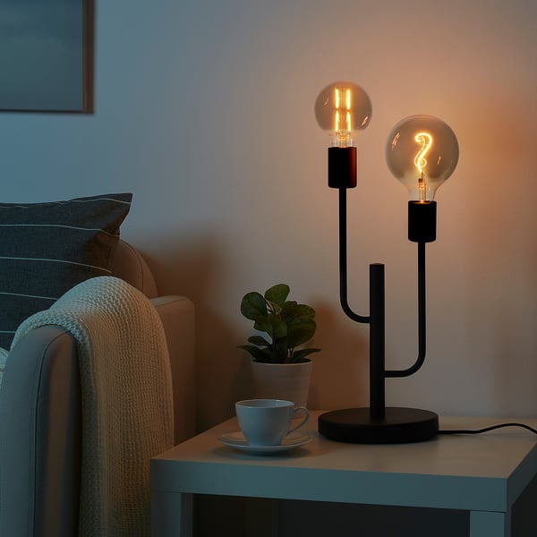 Black HADDEBO lamp with 2 bulbs on side table.